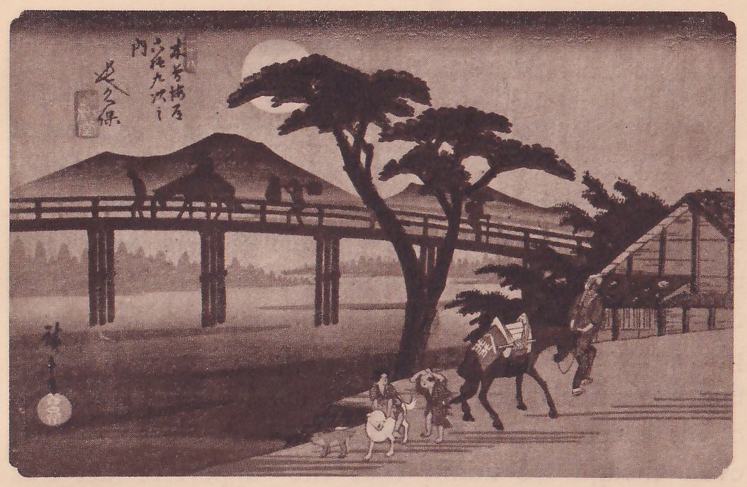 Print of a long wooden bridge on tall posts across a wide river at dusk, with small figures and a horse on the bridge and a round pale moon behind a large pine at the upper center. In the foreground a horse carrying a pack is led along the bank beside a roofed shed at the right, and two small figures walk with white animals at the lower center. Title writing is at the upper left, a signature and seal at the lower left.
