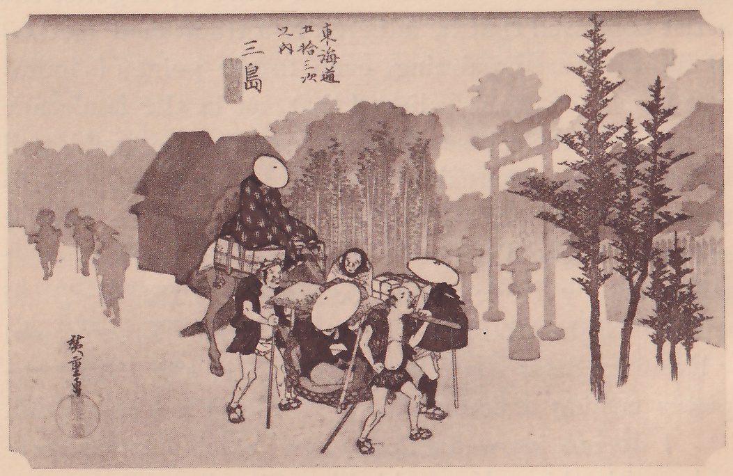 Print of a misty road: at the left a person under a wide round hat sits on a loaded horse, men on foot carry a person in a seat slung from a pole at the center, and faint figures walk off in the haze at the far left. A gate of two pillars and crossbeams and stone lanterns stand in the mist at the right, with tall slender trees in front and a grove behind. Title writing is at the upper center and a signature and seal at the lower left.