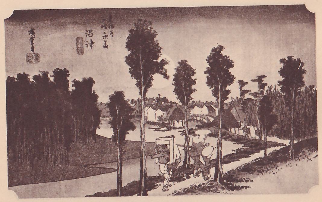 Print of a road at dusk among tall slender trees: a faint pale round moon shows behind the trees at the center, and people walk along a path at the lower right, one carrying a tall frame-like load on the back and others in broad round hats. A dark grove and a river bend lie at the left, with thatched houses, white-walled buildings and an arched bridge in the distance. Title writing is at the top and a signature and seal at the upper left.