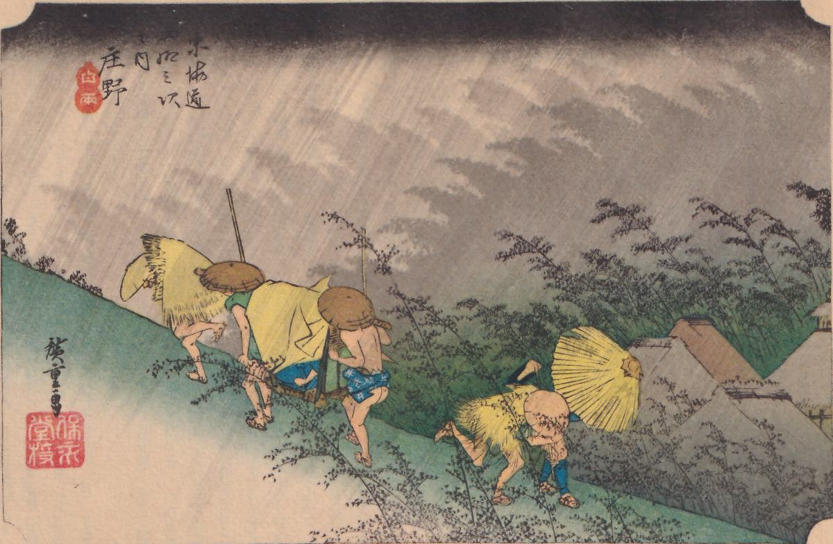 Colored print of a heavy rainstorm over a green hillside: gray rain streaks slant down from a dark sky, and tall bushes and grasses bend along the slope. At the left a group of men in straw capes and round hats hurry along the slope, with a long pole carried among them. At the lower right bent figures struggle against the wind beside a large yellow umbrella blown open, and thatched roofs show at the right. A title cartouche and a signature with a red seal are at the upper left and lower left.