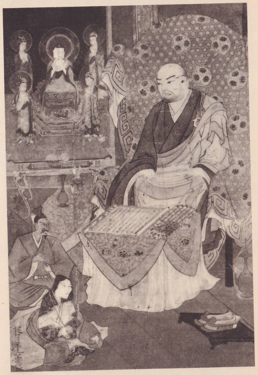 Faded painting of a large seated bald man in dark and pale robes on a chair covered with a round-patterned cloth, with a flat gridded panel on a cloth before him; at the lower left a man in a dark robe and black cap sits beside a seated woman with long hair, and at the upper left a small altar scene shows a seated haloed figure with standing haloed figures at both sides.