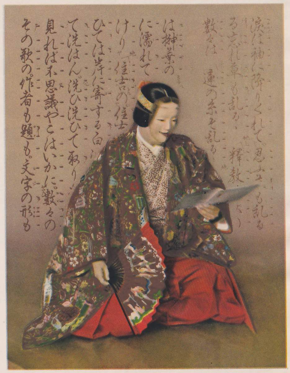 Colored painting on a tan ground of a kneeling figure with a pale, mask-like face and dark hair in a rounded knot with a striped band, turned toward the viewer's right and looking down at a folded gray paper held in the hand at the viewer's right; the robe is brown and covered with colored embroidery over a red lower garment, and the other hand holds a fan with black ribs low at the viewer's left. Behind the figure runs a page of the Noh chant book for Sōshi-arai in several vertical columns of brushed writing with chant marks beside them: the chorus at the moment she washes the poem book.