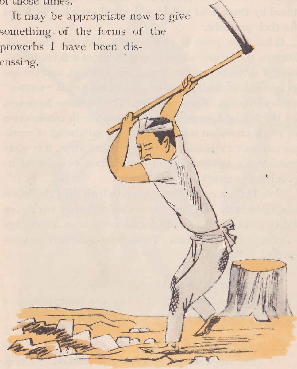 A man with a cloth tied around his head swings a long-handled hoe up over his head, standing on rough, stony ground beside a tree stump.
