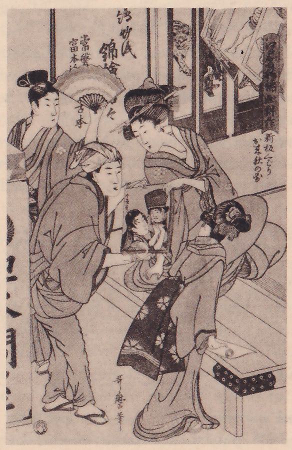 Black-and-white print of several figures in a shop. At the left a figure with a cloth around the head, in a loose robe, bends forward holding up a small framed picture that shows two small figures; behind this figure another figure with the hair in a knot stands holding a fan, and a figure leans in from the upper center. At the lower right a figure with the back turned, in a robe patterned with flowers, stands with a very wide round shape behind the head. Hanging pictures and sign boards fill the upper left and right. Columns of Japanese characters stand at the upper left and the right, with a signature column at the lower center and a seal at the lower left.