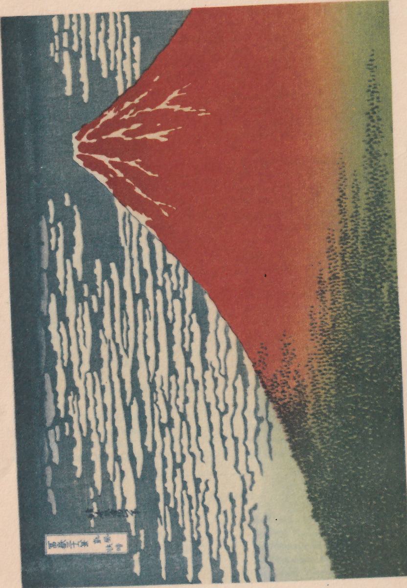Colour print, shown sideways as it is printed on the leaf. A large mountain with a pointed peak toward the left slopes down toward the right: its body is red, fading through orange to green at the right edge, and thin white streaks run down from the peak like branches. A band of dark green dots lies along the right and lower right. A blue-grey area at the left carries long rows of white cloud shapes. A small box of Japanese characters stands at the lower left corner, with a short line of small Japanese characters above it.