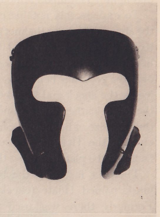 The upper right of three black-and-white photographs on the page: a smooth black curved plate with a T-shaped opening cut through its middle and two narrow pieces hanging at the lower sides.