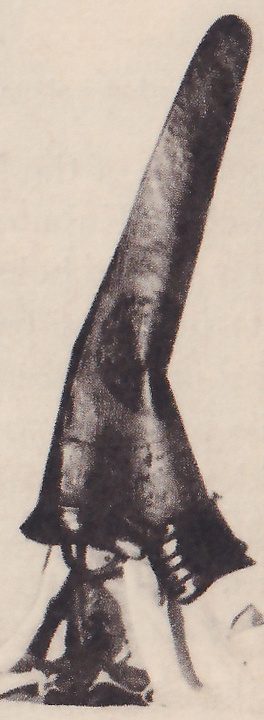 The lower right of four black-and-white photographs on the page: a tall dark slanting cone, rounded at the tip and widening toward its base, with a few small ladder-like marks at its lower right, standing on pale shapes.