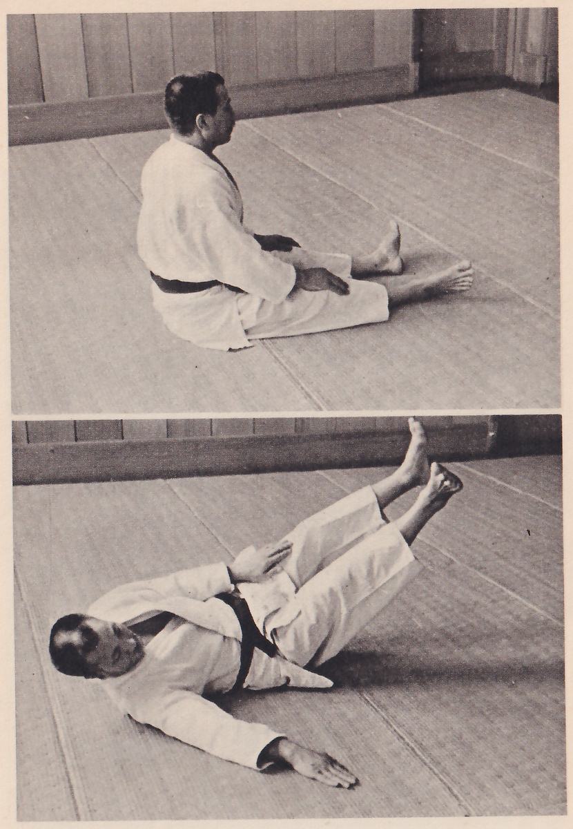 Two photographs, one above the other. In the upper one (1a) a man in a judo suit sits on a mat seen from the side, legs stretched out and hands on his knees. In the lower one (1b) he lies on his back with his legs raised and one arm stretched along the mat.