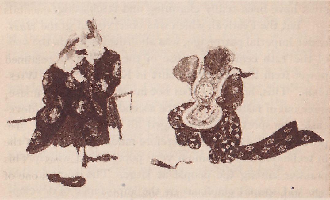 Painting of three figures in dark robes patterned with small round flower shapes. At the left two stand close together in tall black caps, one with a hand raised to his face, a sword hanging at the side of the nearer one. At the right a third figure with a dark face crouches in a stepping pose, a pale breast piece with a large round design on his chest, a hand raised at the level of his head, and a long patterned sleeve or sash trailing out to the right. A small dark object lies on the ground between them. Faint lines of printed text from the other side of the leaf show through the whole picture.